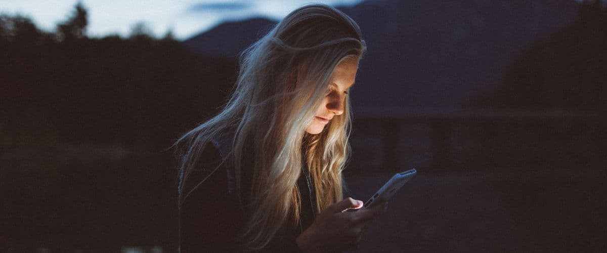 girl's face light up by the light on her phone