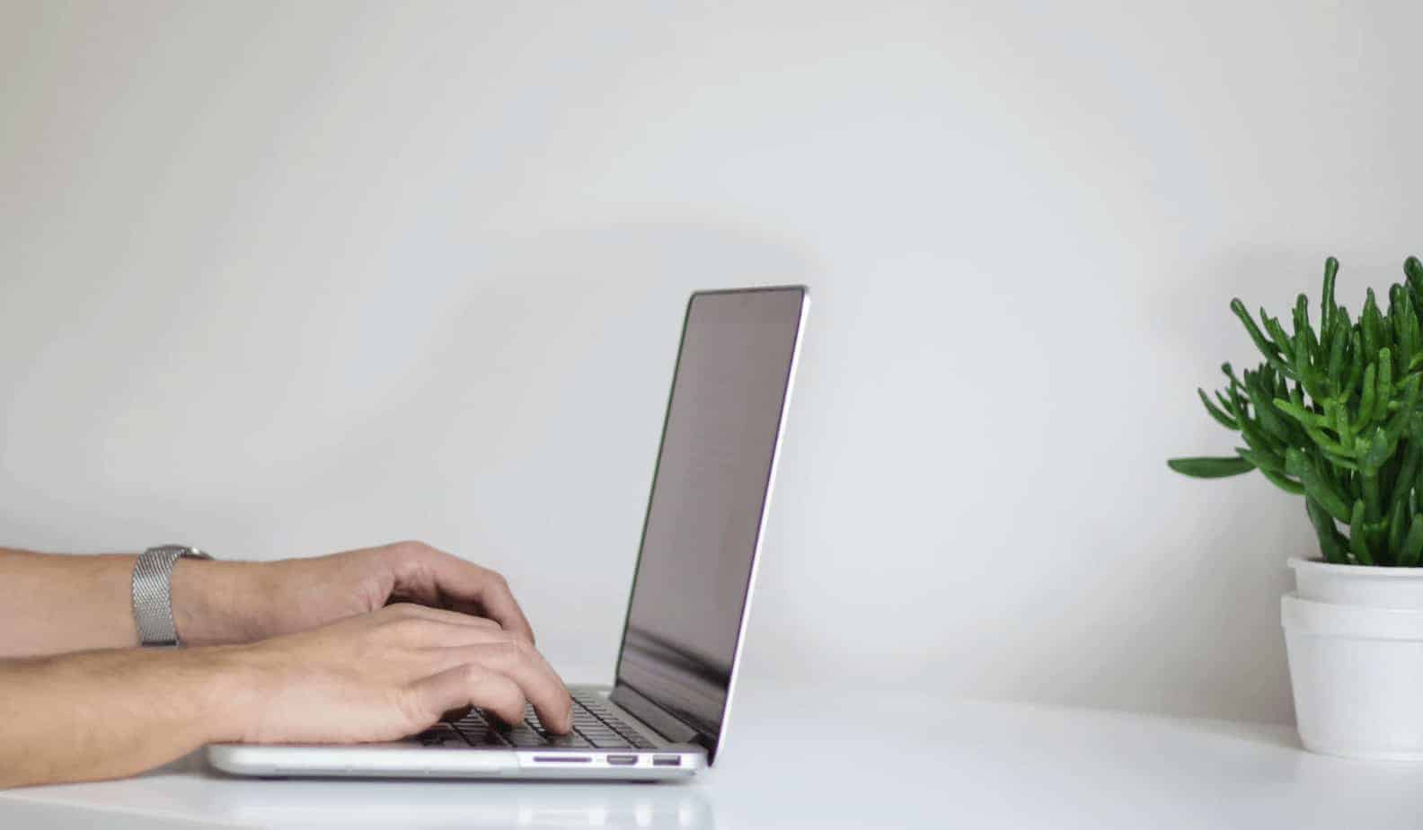 hands writing on a gray computer