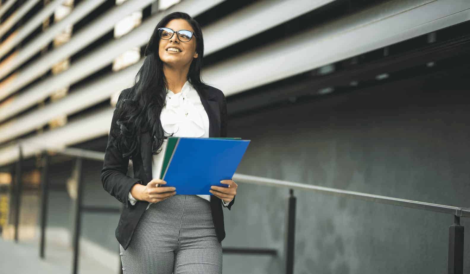 Business woman working in street holding folders looking in that distance