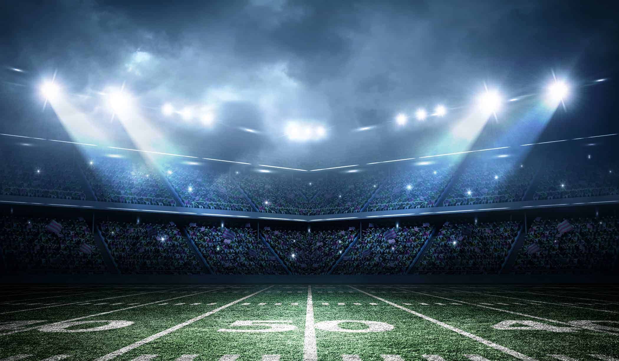 view from the 50 yardline on a football field looking at a full stadium with lights on