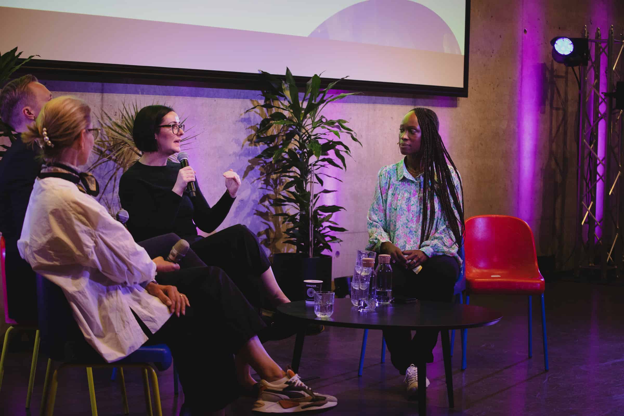 Aimee Meester speaking to two women around a desk at a conference