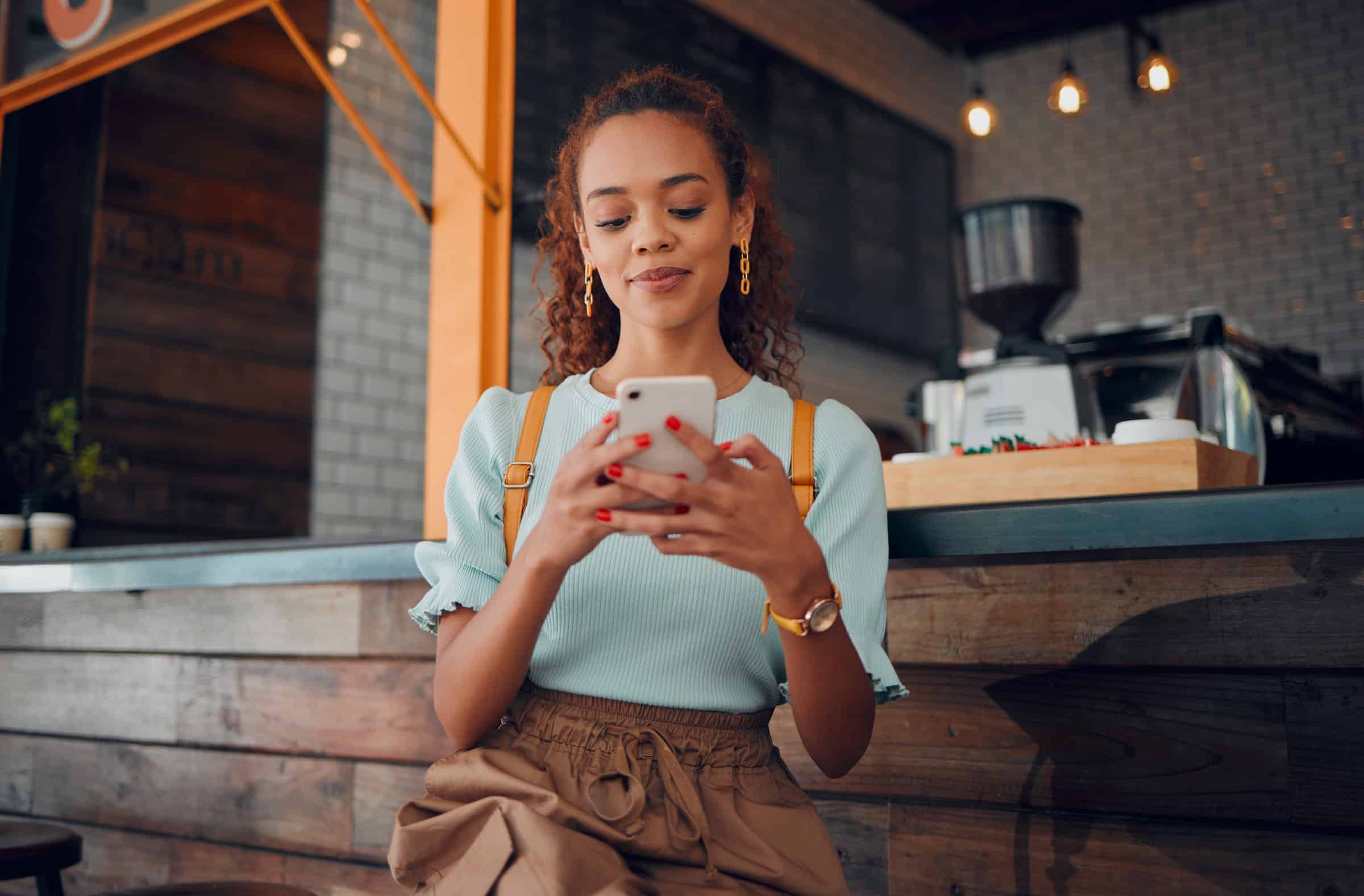 Phone, social media and coffee shop with a woman typing a text message while sitting in a cafe to relax. Internet, mobile and communication with a young female customer in a restaurant texting.