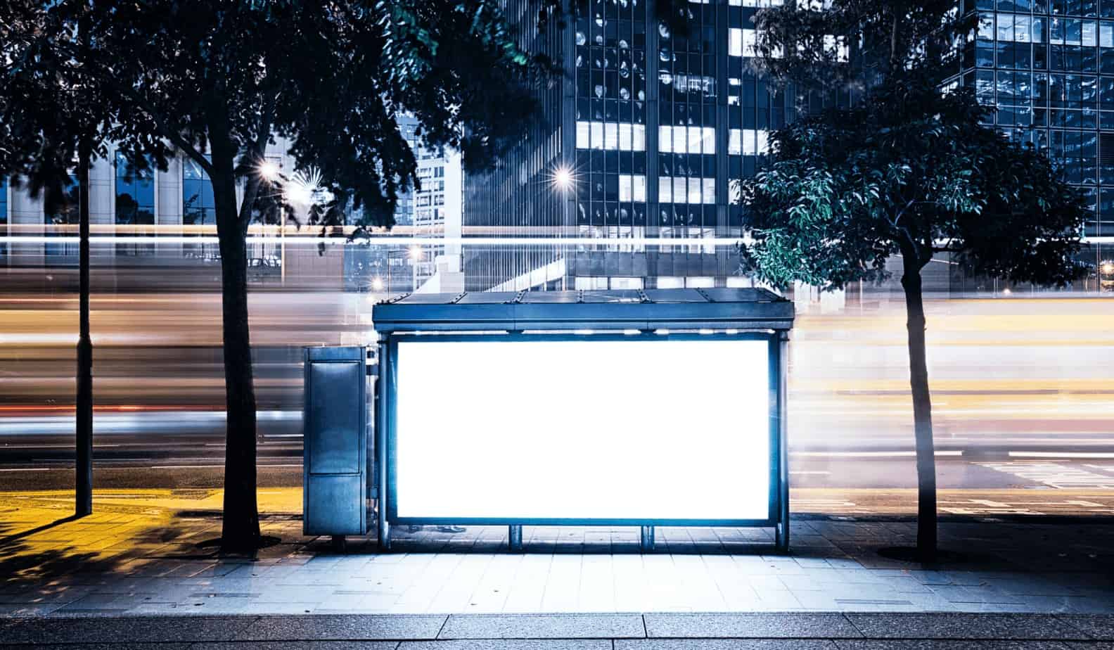 White billboard in busy city with blurred cars driving by