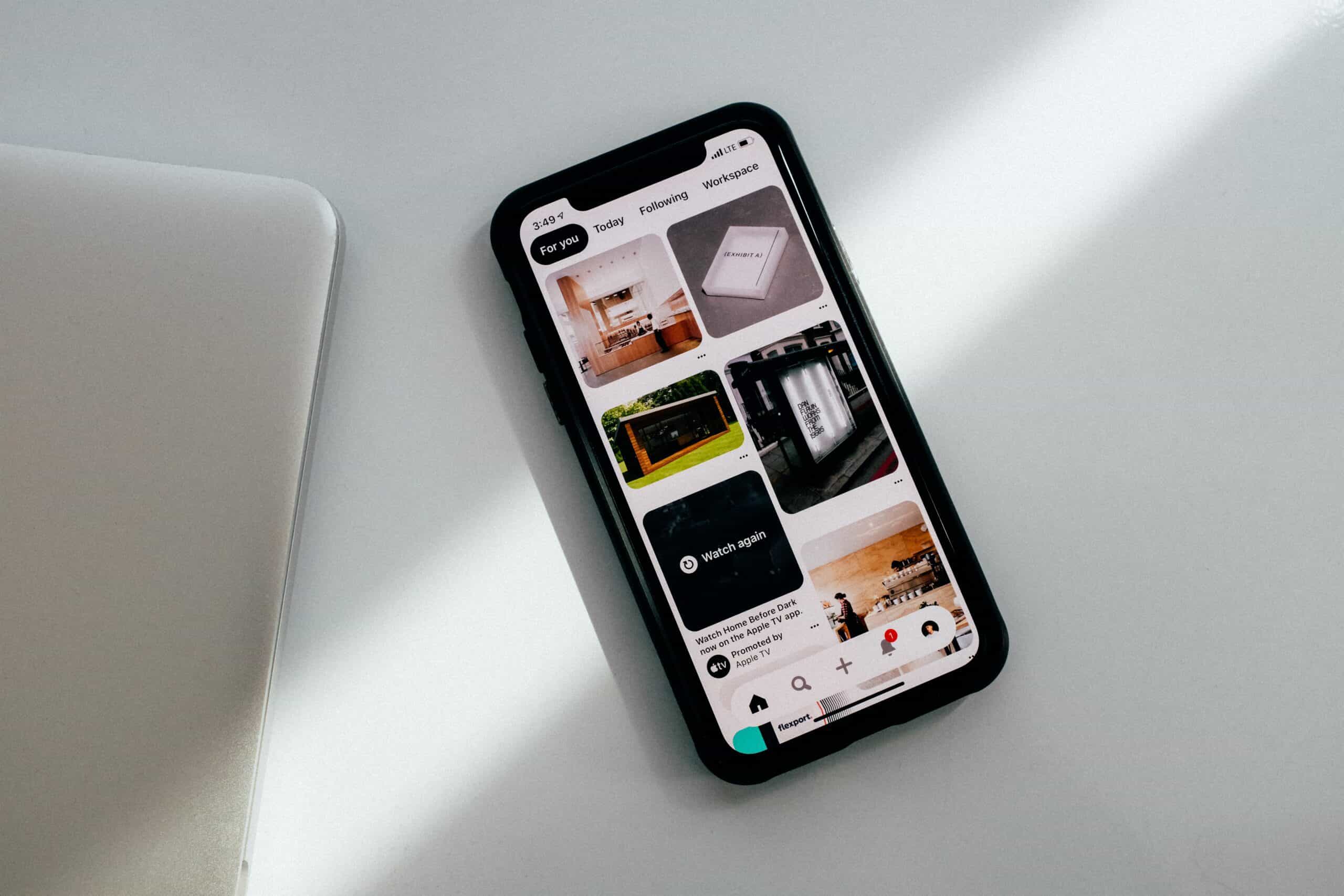 Black phone on a white table opened to a "for you" page