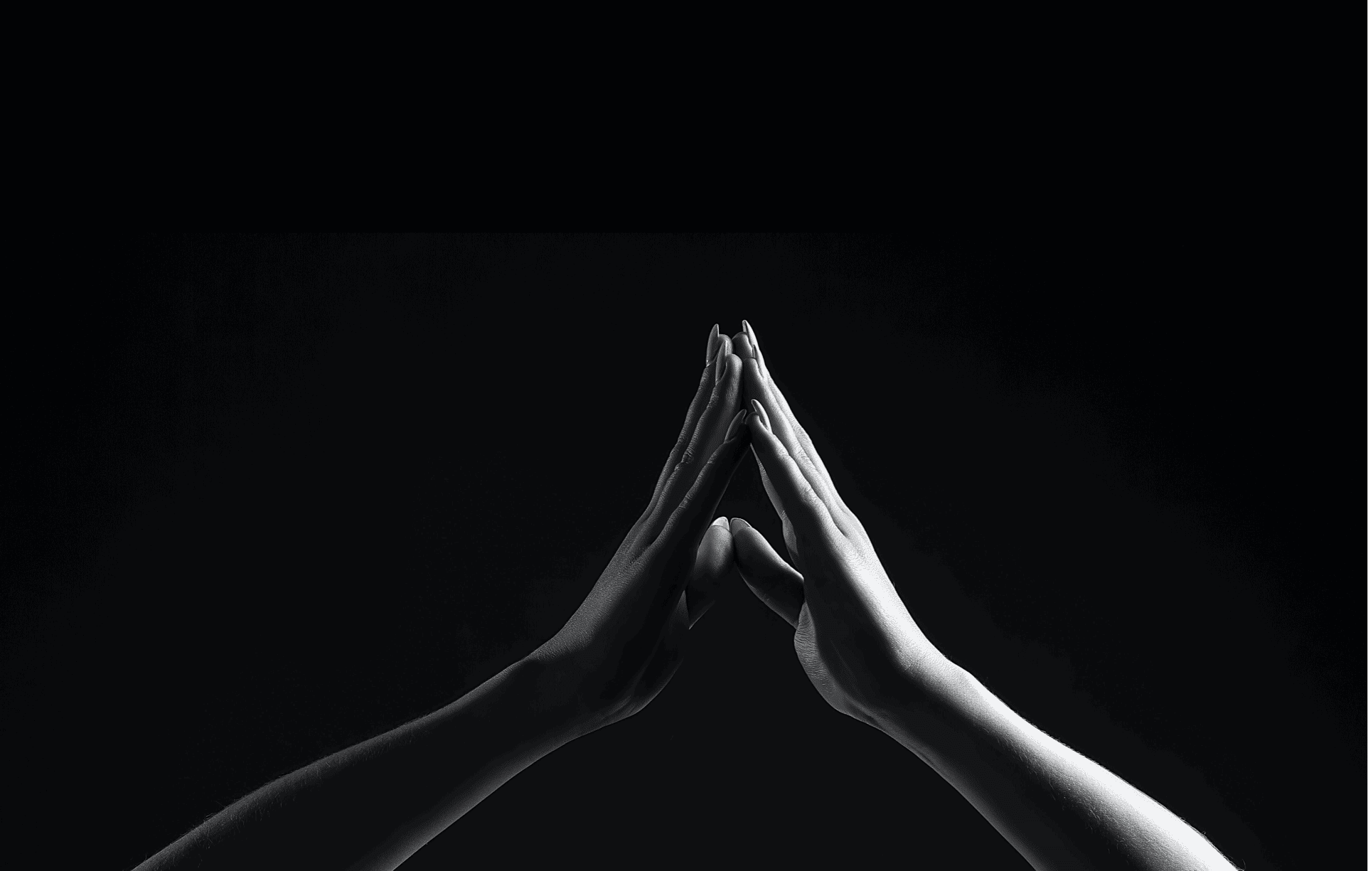 black and white hands in a "prayer" placement in front of a black image