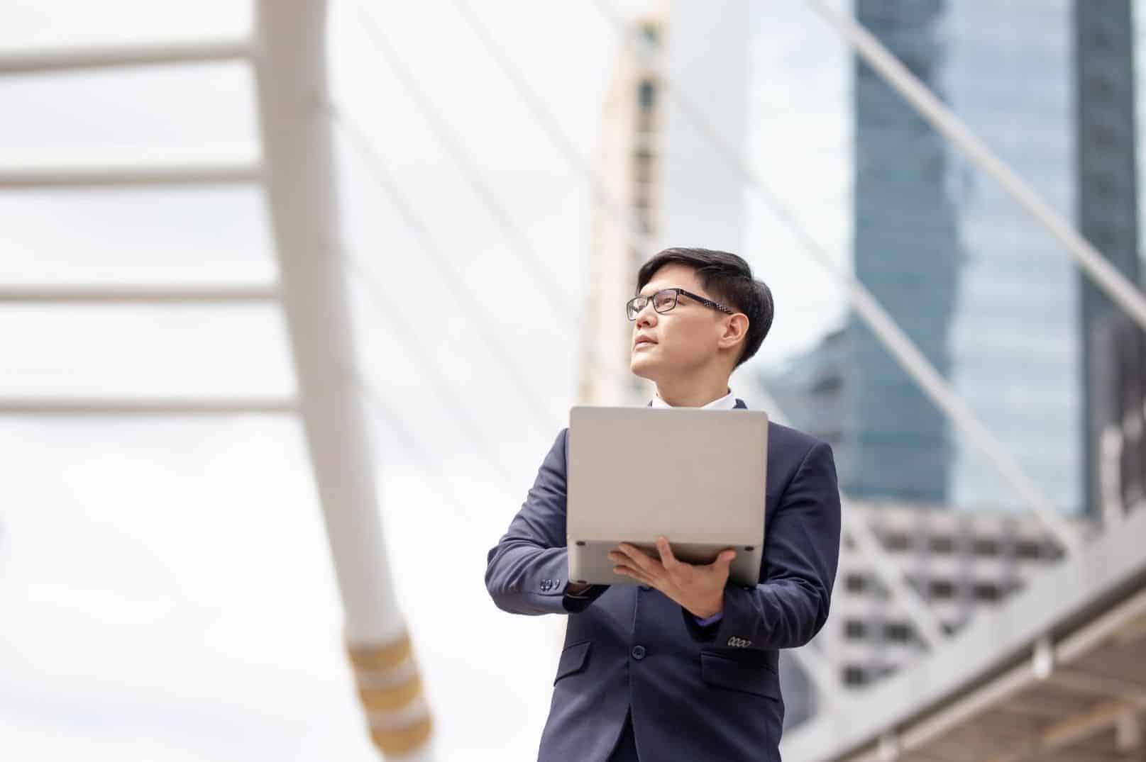 man in suit holding laptop