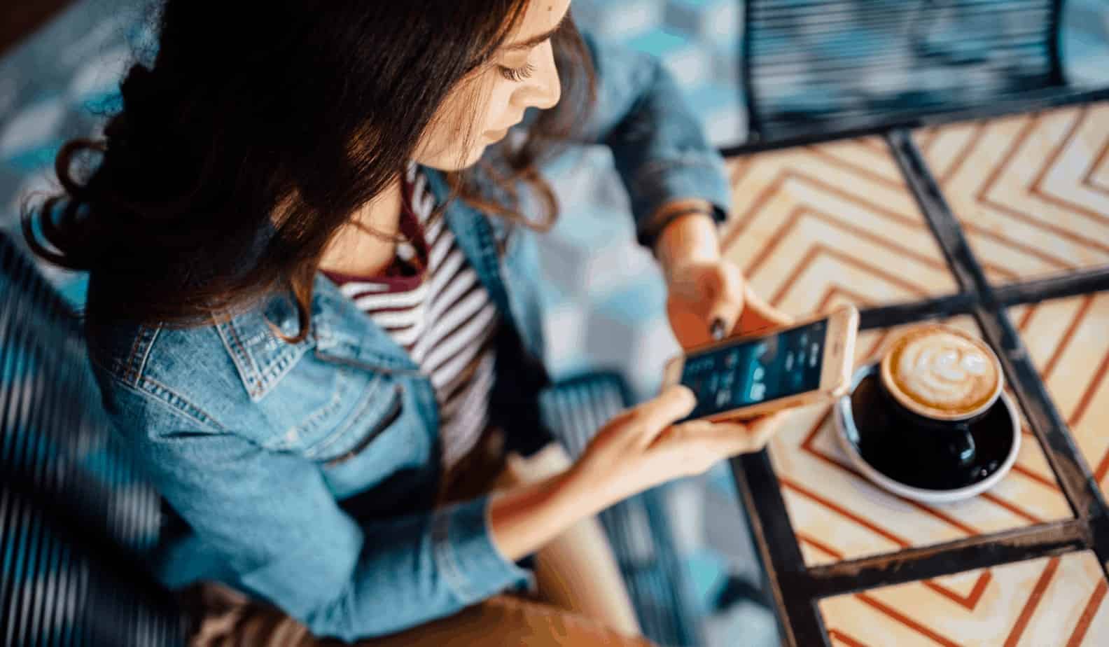 women looking at her phone drinking coffee