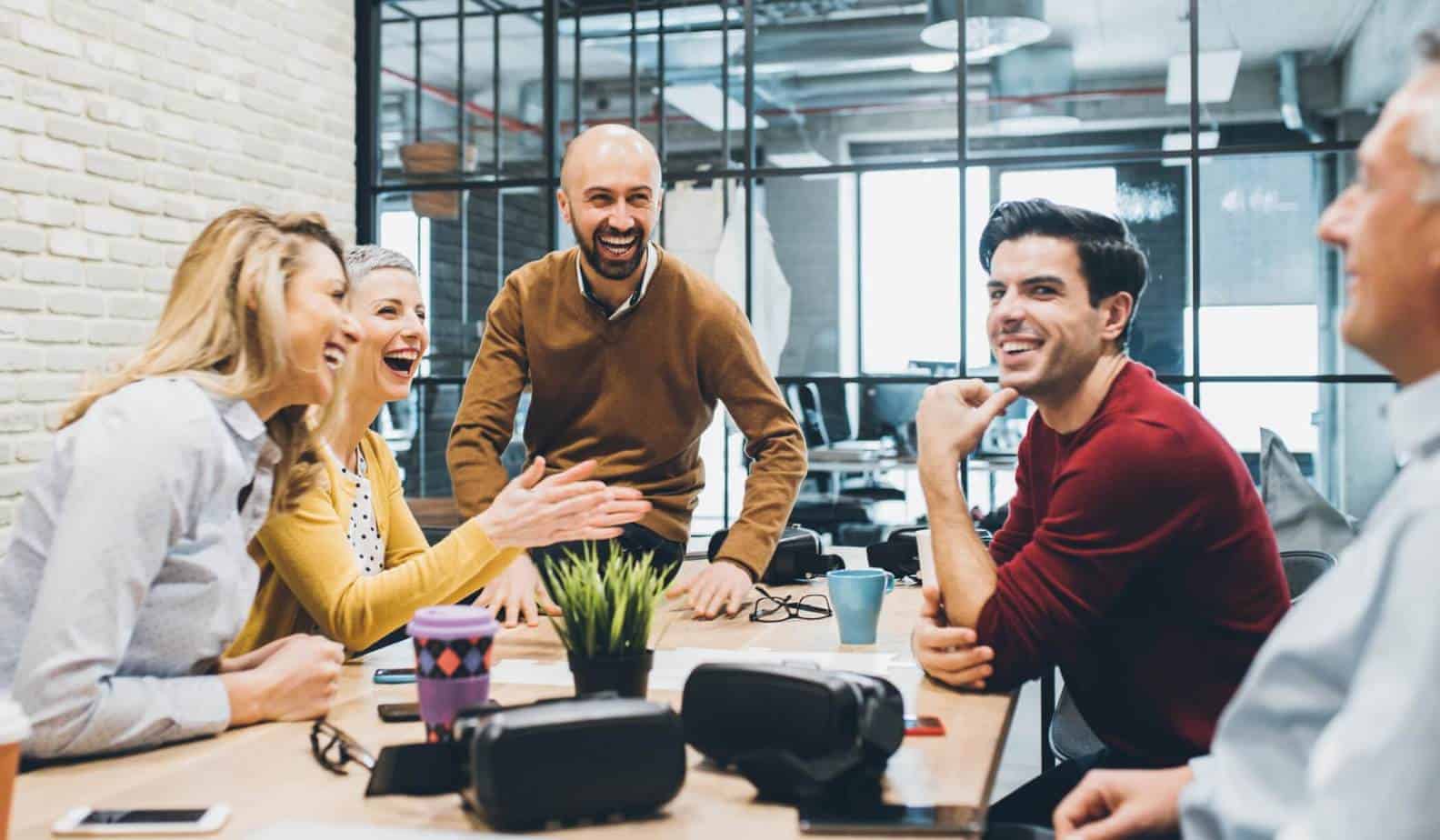 five people sitting at a table having a meeting