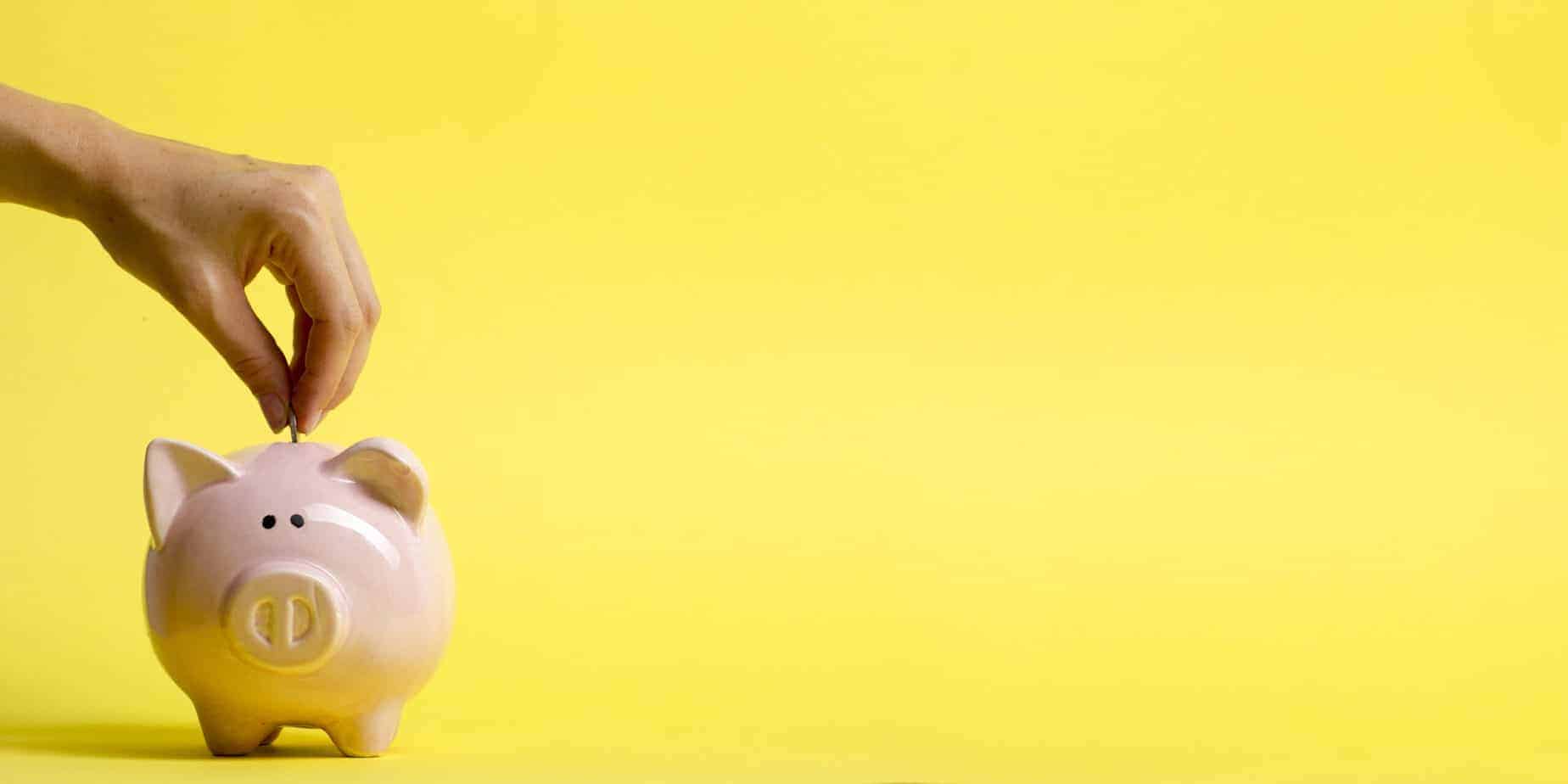 woman hand putting money coin into piggy for saving money wealth and financial concept.