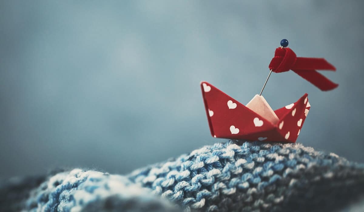 small red boat on waves of woven material