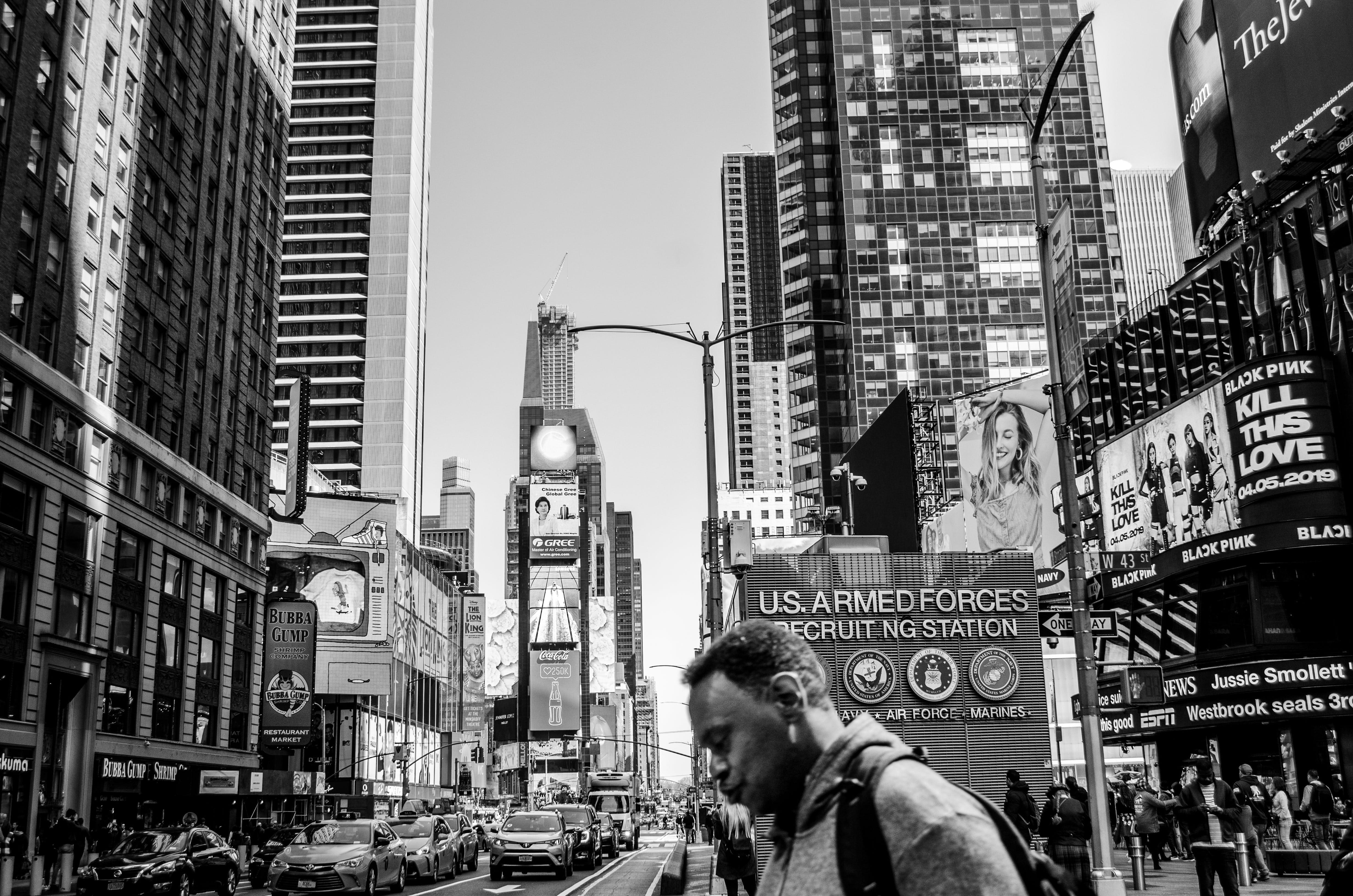 Black and white image of a busy city with advertisements displayed on billboards