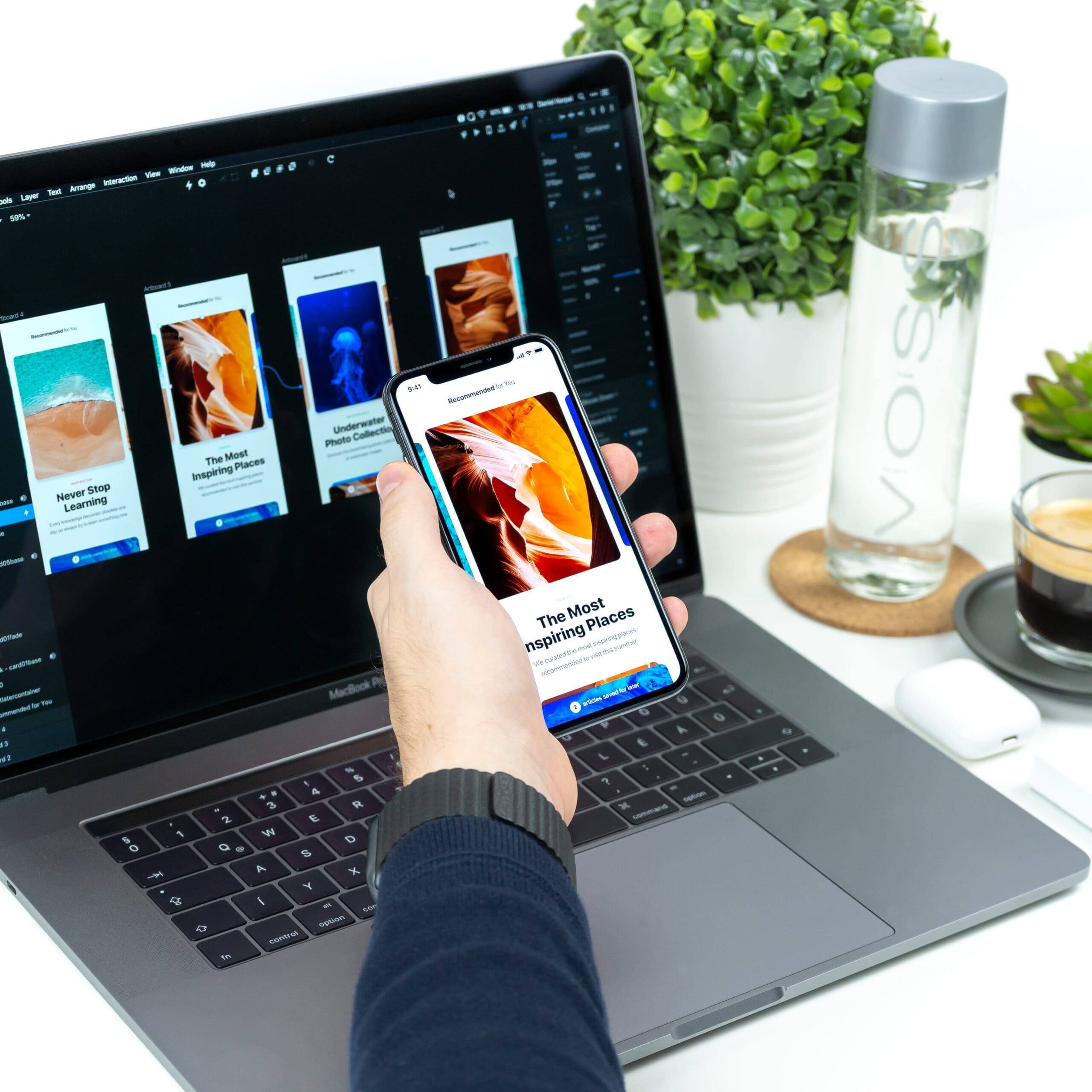 Laptop screen behind a hand holding a phone