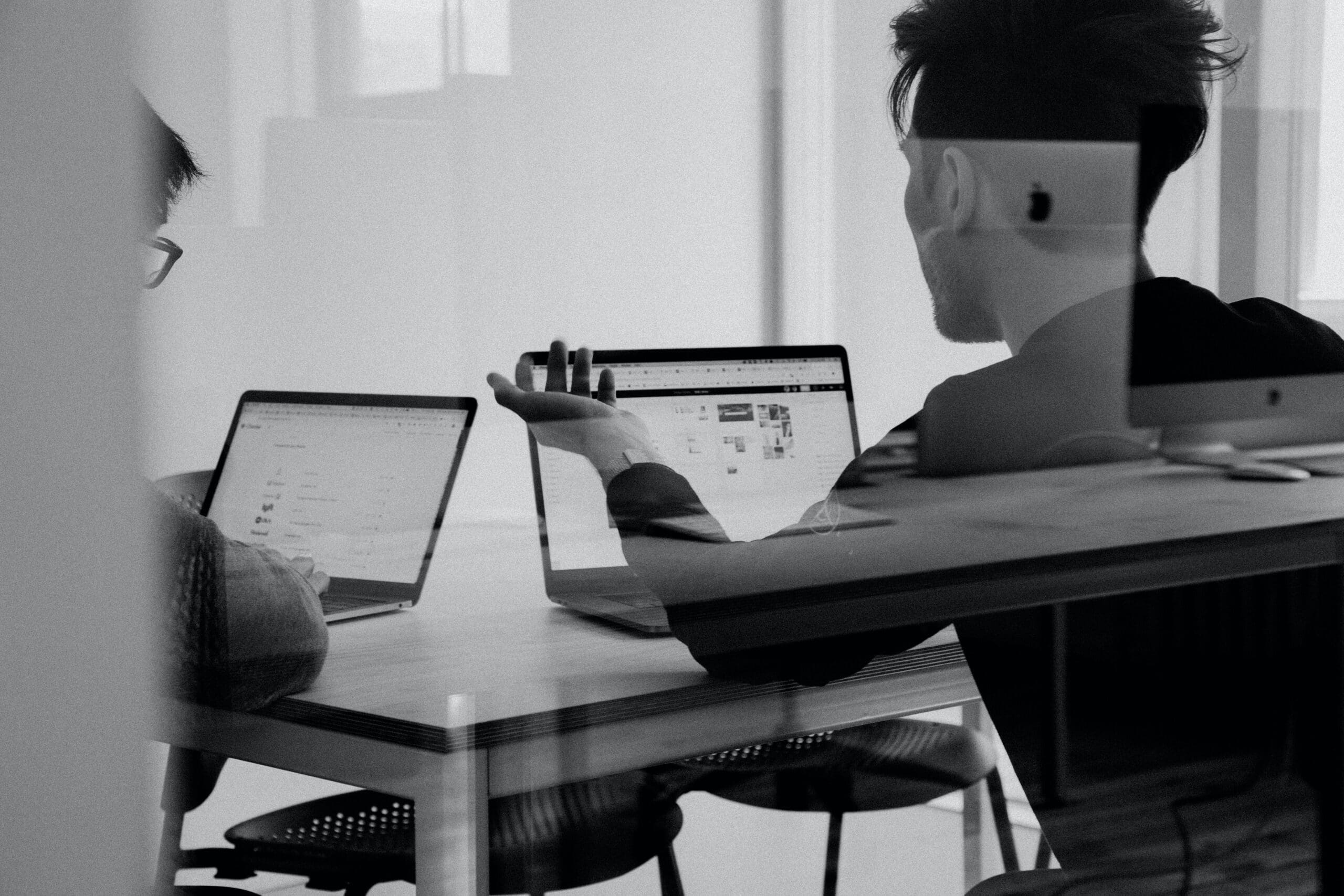 Two people working on laptops at a table