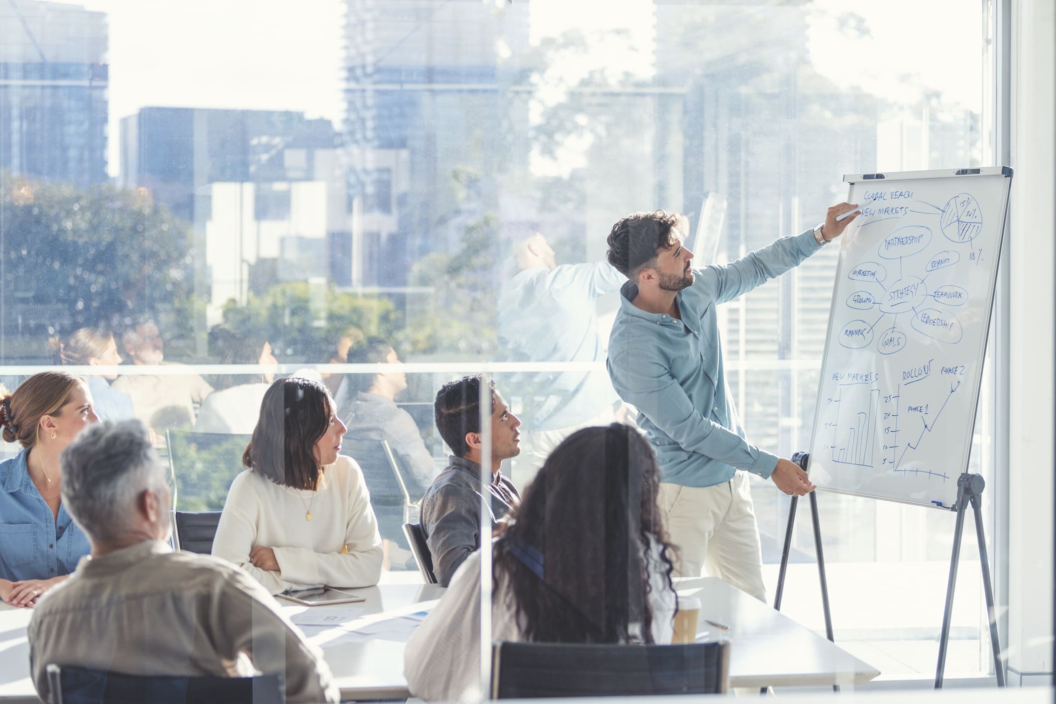 group of people watching man work at a whiteboard